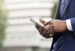Black businessman browsing internet on smartphone outdoors